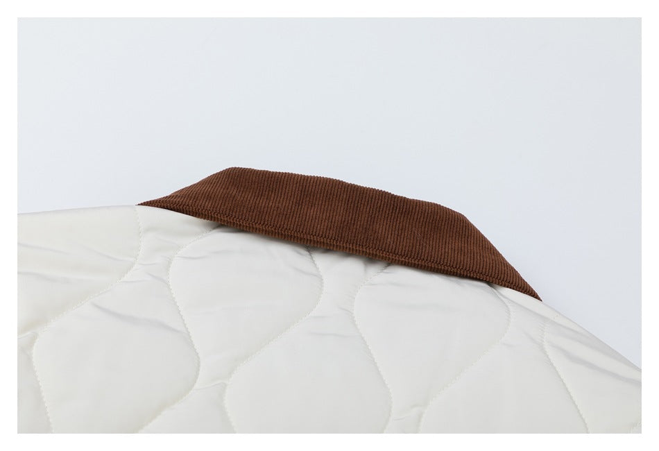 Close-up of a white quilted garment with a wide brown ribbed collar.
