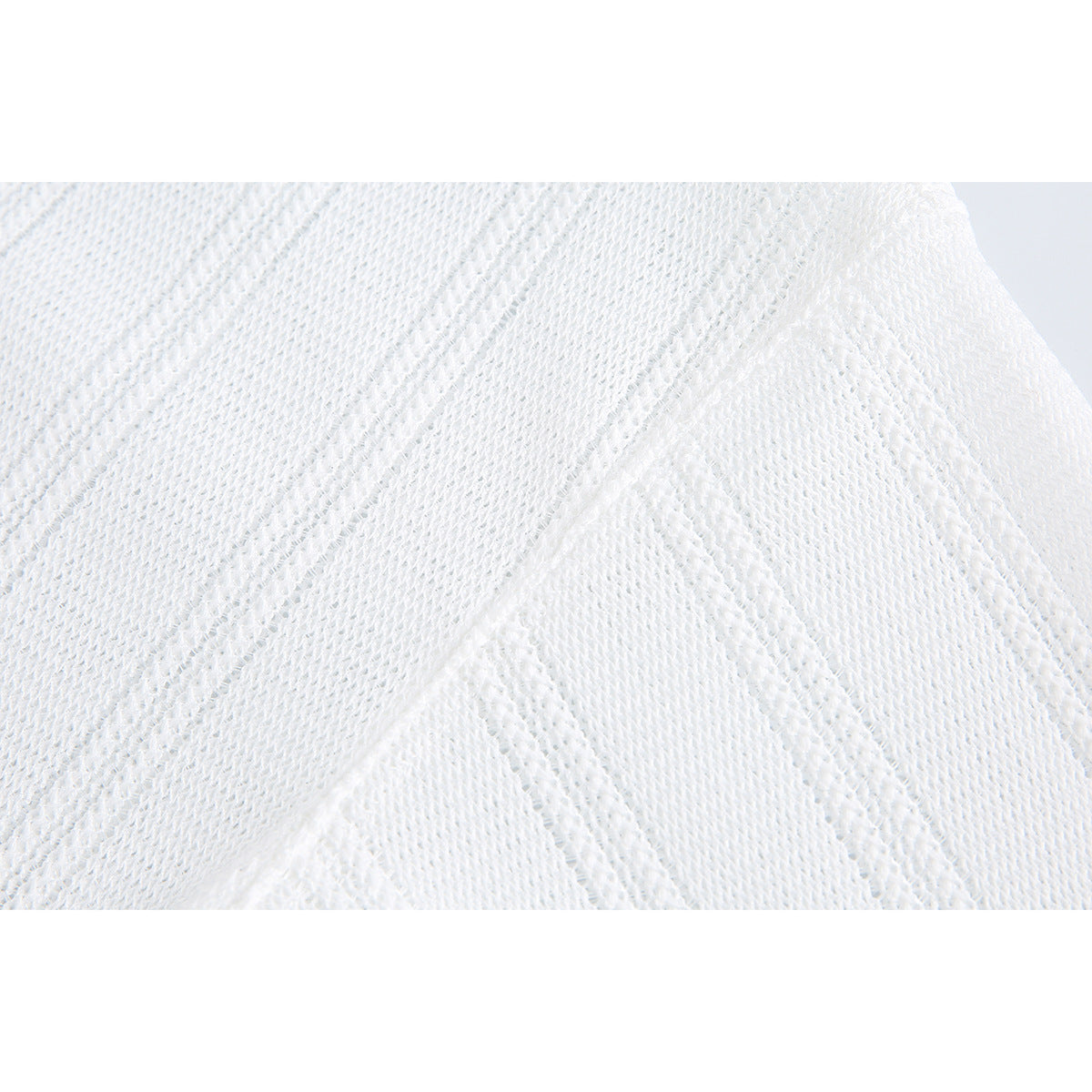 Close-up of textured white knit fabric with alternating open and raised vertical stripes.