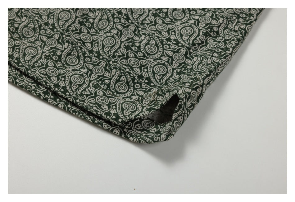 Close-up of the stitched edge and opening on dark green pants with a cream paisley print.