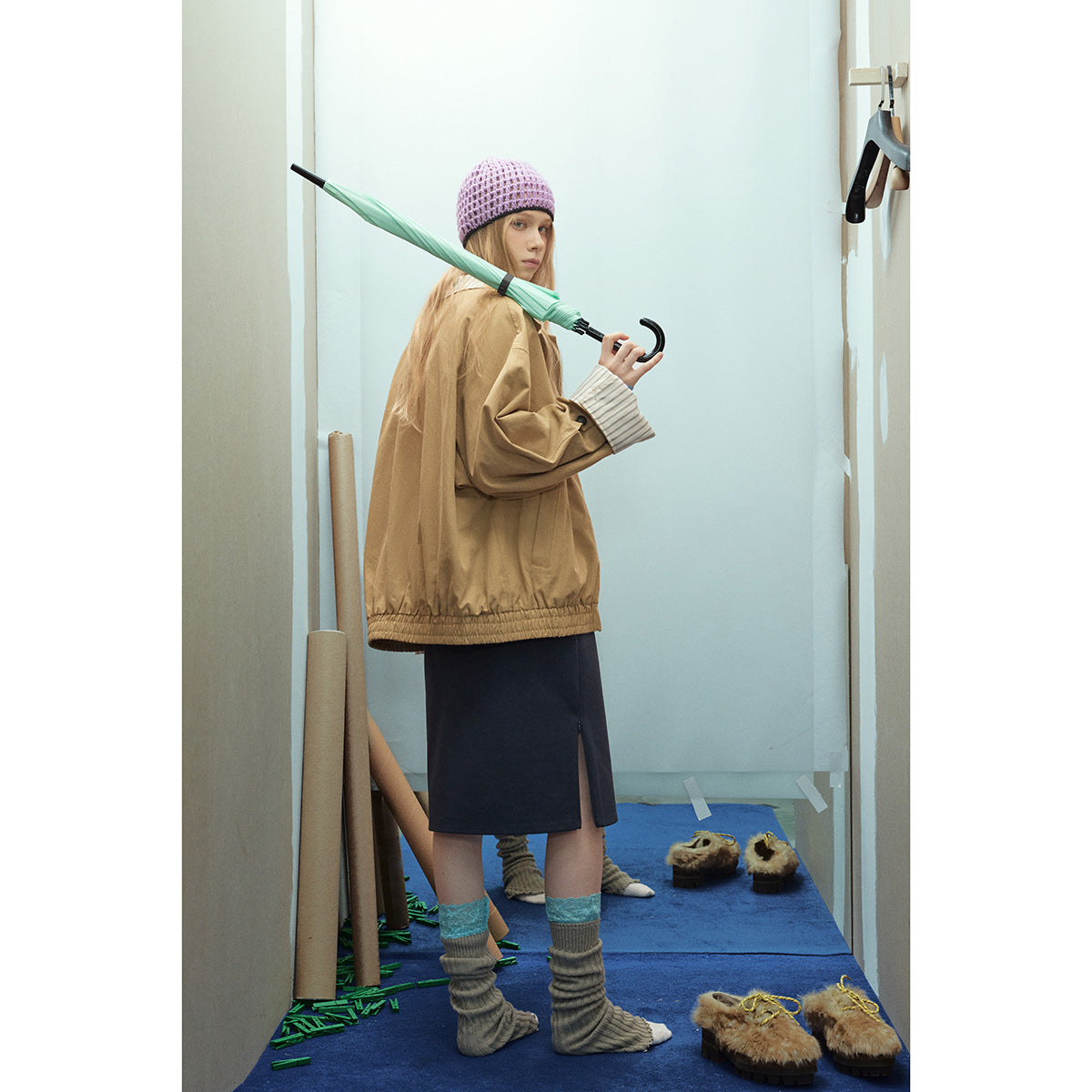 Model shown from the side and back in a tan jacket with striped cuffs and hem, holding a mint umbrella.