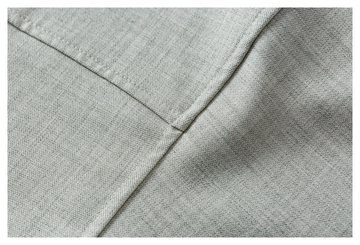 Close-up of stitched seams on light gray woven shirt fabric.