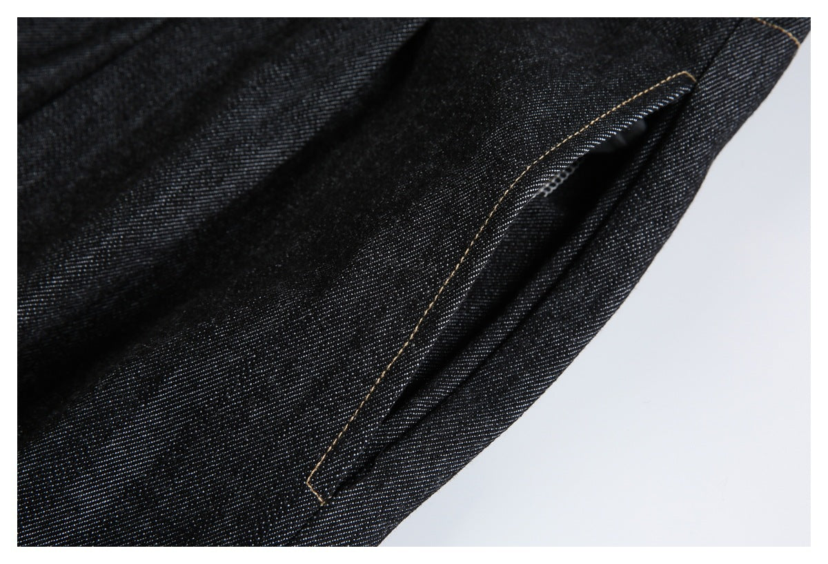 Close-up of a slanted pocket on dark indigo jeans with tan contrast stitching.