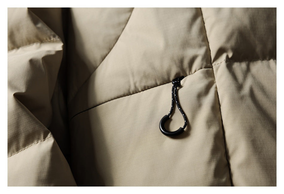 Close-up of a black drawcord toggle on a taupe quilted puffer jacket.