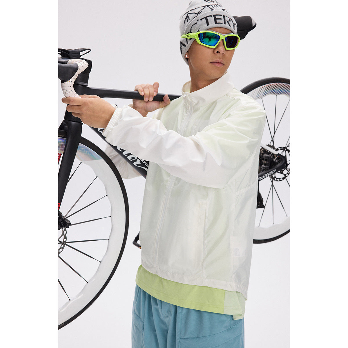 Close view of a cyclist in a white jacket and blue shorts holding a road bike.