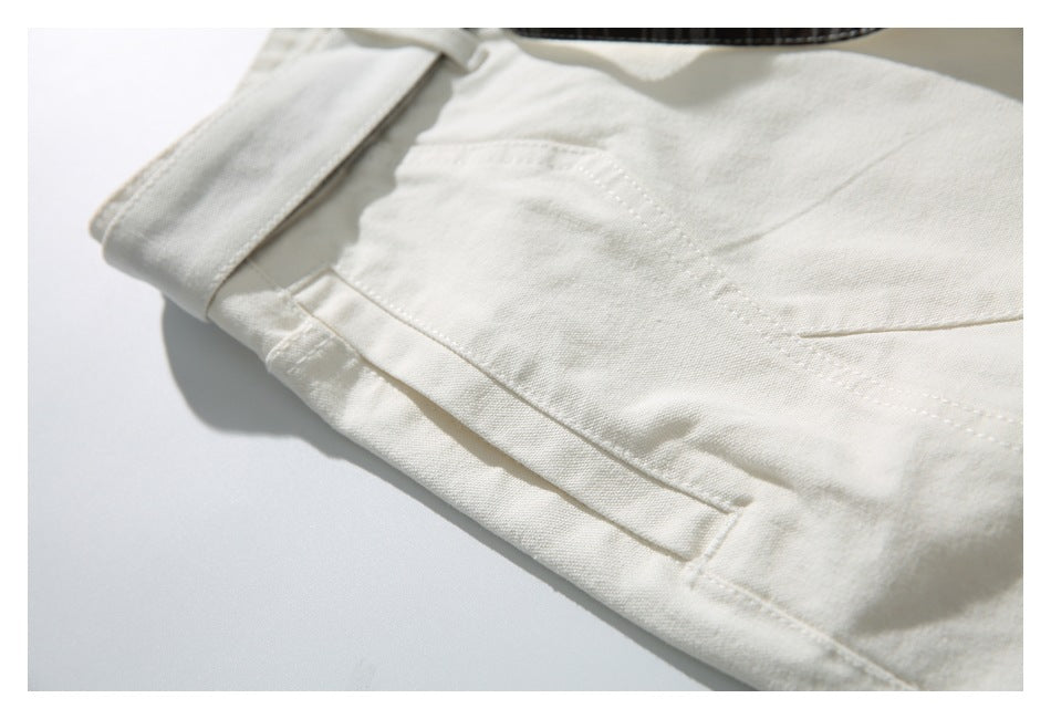 Close-up of an ivory shorts pocket and belt loop, with a glimpse of dark plaid trim.