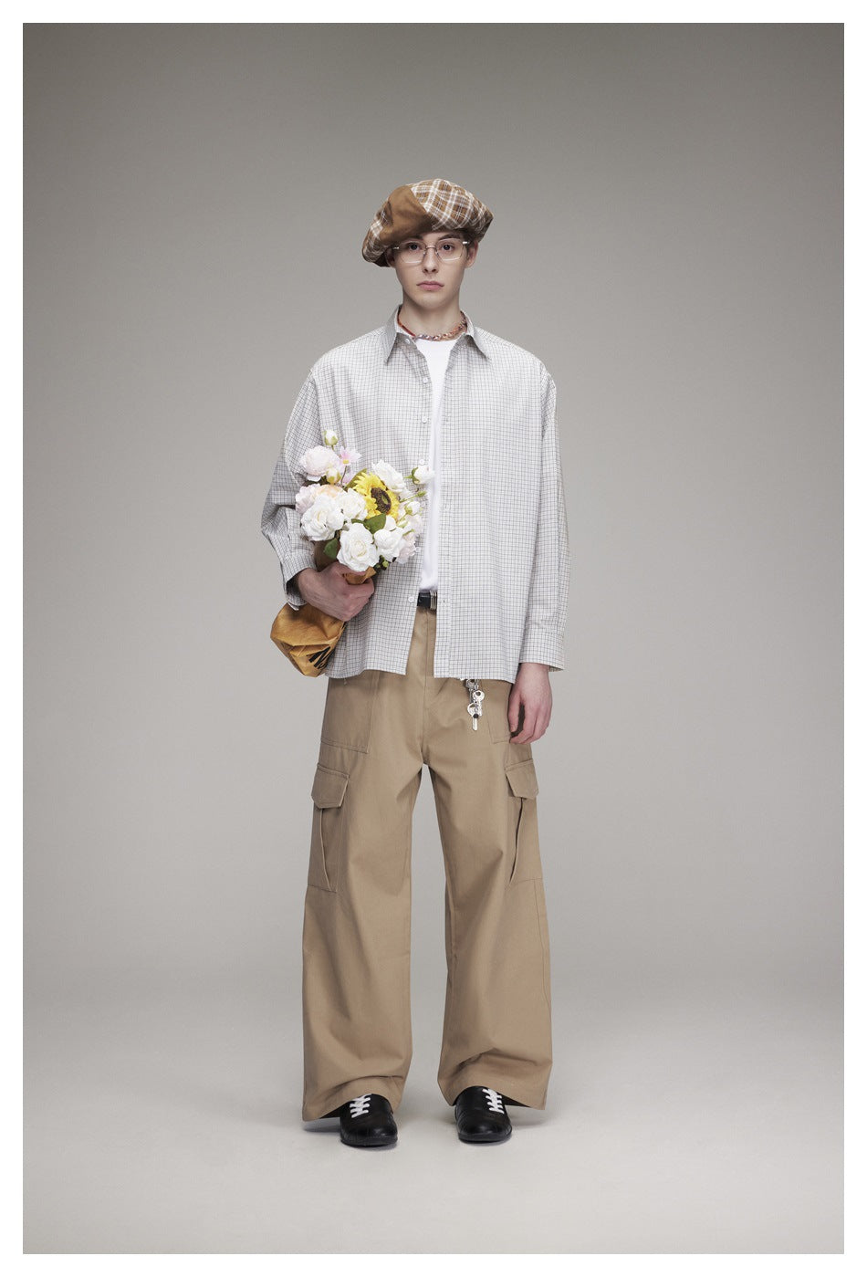 Front view of a model in a light gray checked shirt and loose tan cargo trousers.