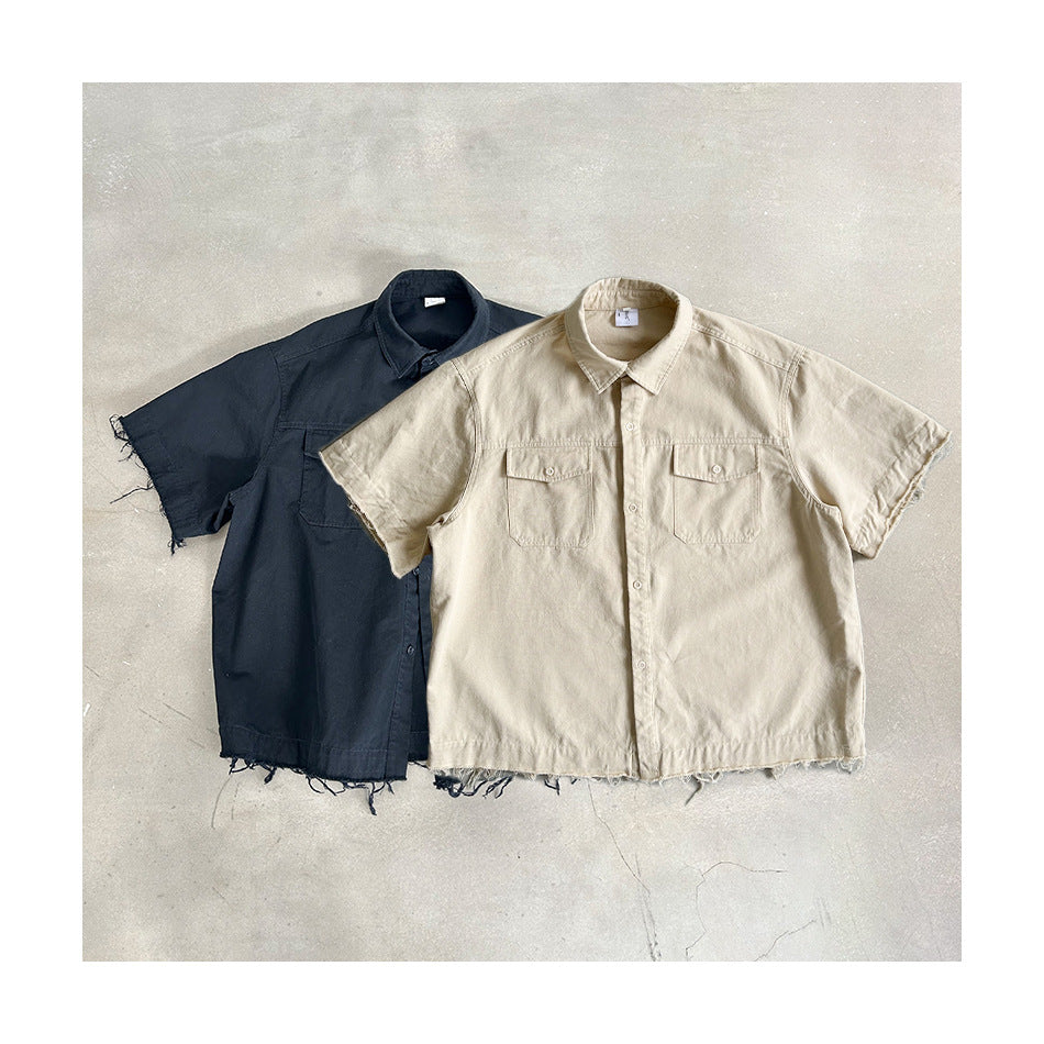Black and light khaki short-sleeve work shirts laid flat on concrete, showing raw frayed hems and sleeve edges
