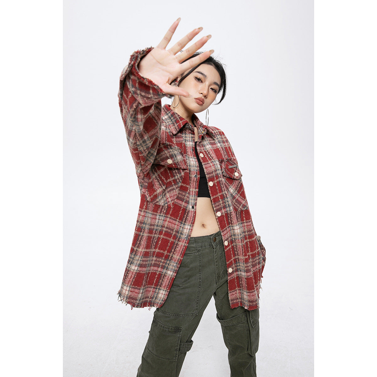 Model wearing an oversized red, gray, and cream plaid shirt jacket with snap buttons and flap pockets.