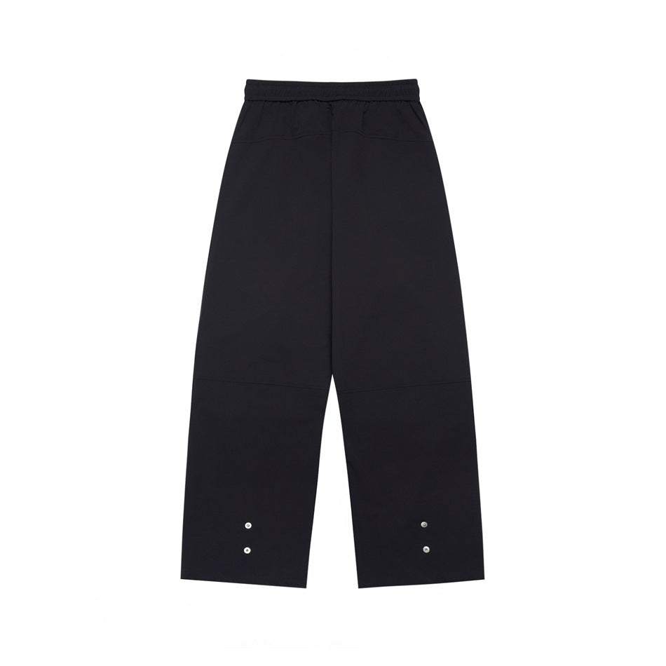 Back view of black wide-leg pants with an elastic waistband and small snaps near the hems.