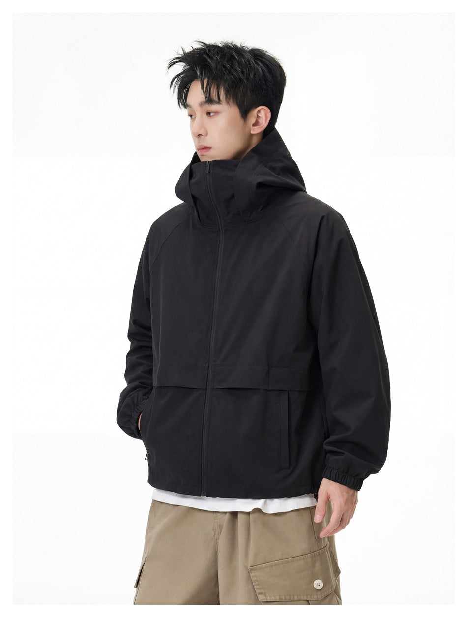 Model in a black hooded zip jacket and beige cargo trousers, shown from a slight side angle.