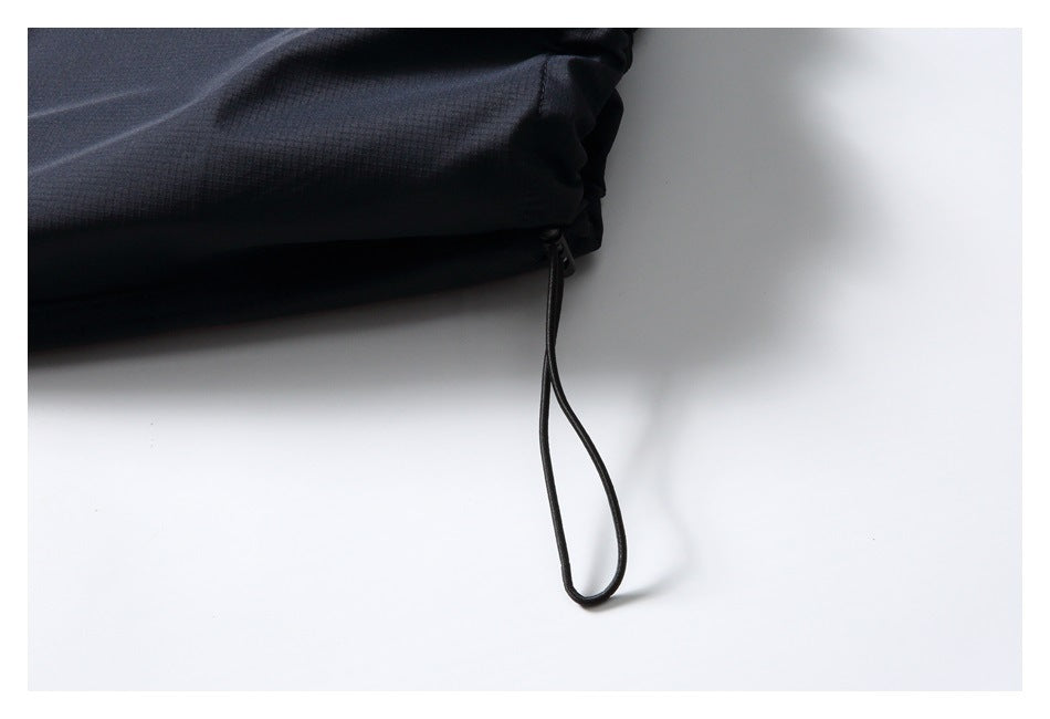 Close-up of a looped drawcord hanging from the elasticated hem of dark trousers.