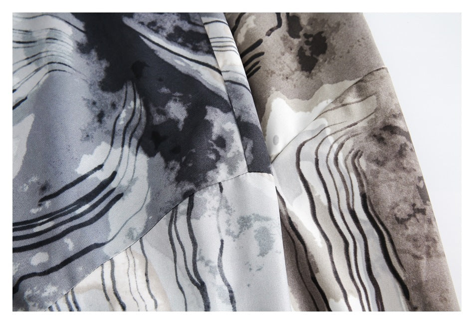 Close-up of the abstract-print shirt's sleeve and overlapping fabric panels in gray, black, and cream.