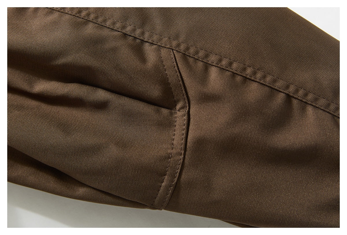 Close-up of curved stitched seams on brown garment fabric.