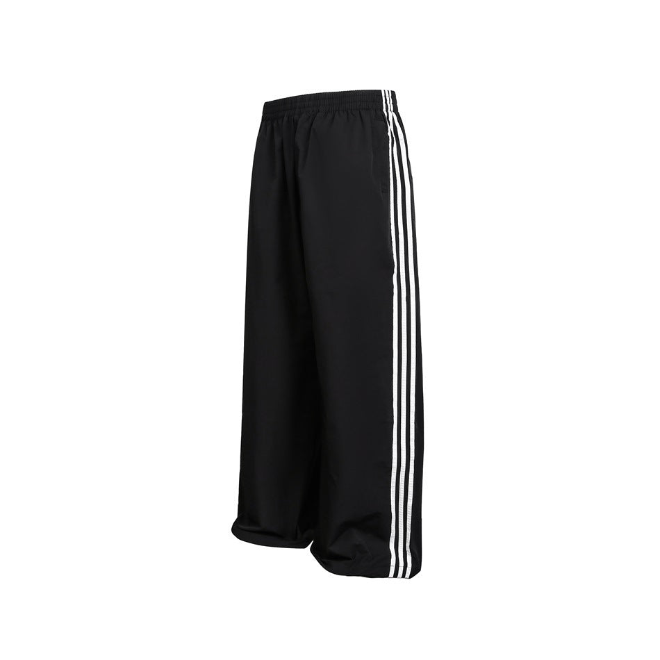 Angled view of black wide-leg pants showing three white stripes along the outer leg.