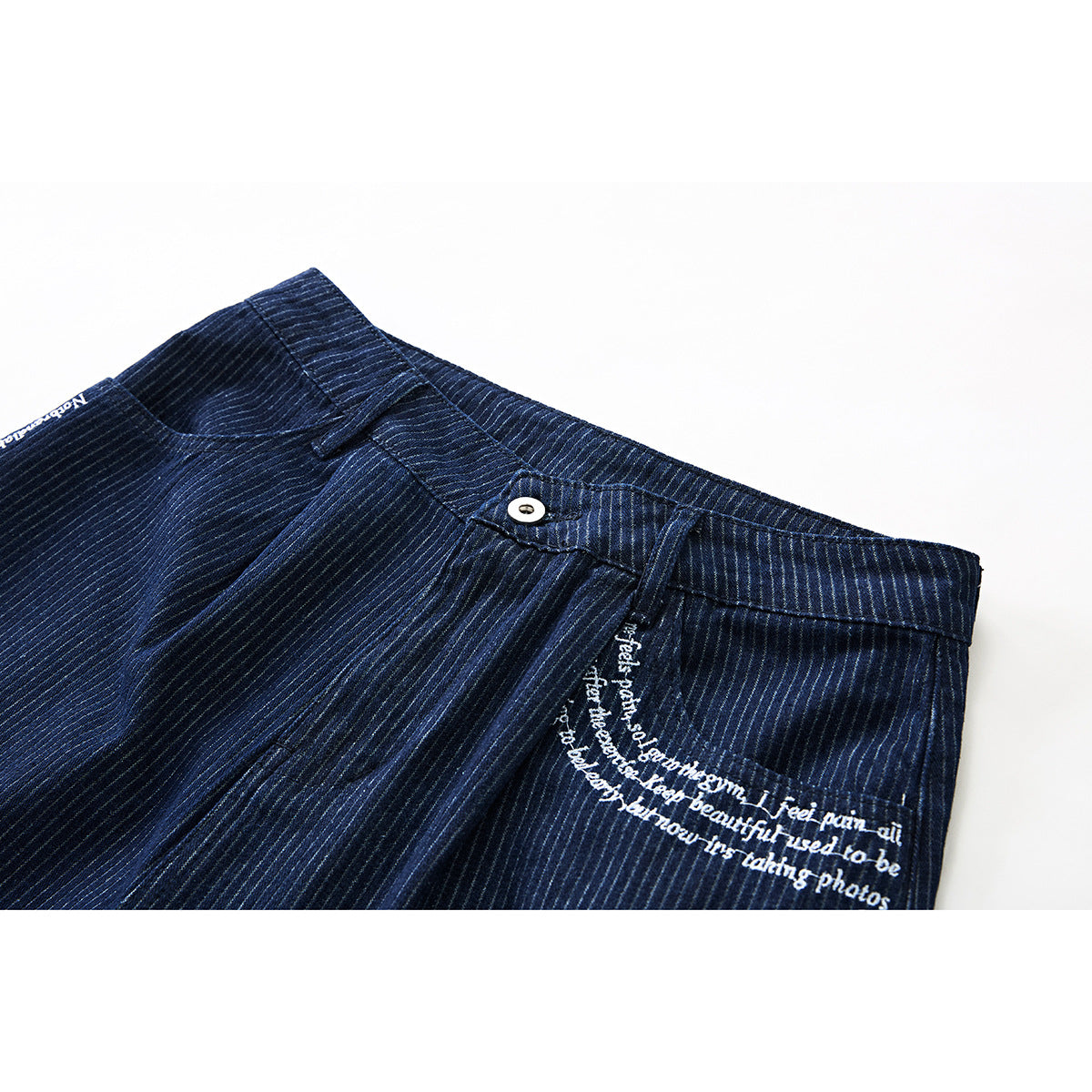 Close-up of navy pinstriped shorts showing the waistband, button, front pocket, and white script on the pocket.