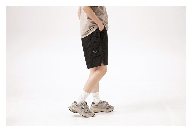 Side view of a model wearing black shorts with a flap pocket and a small label on the leg.