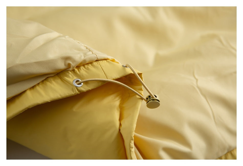 Close-up of the yellow jacket’s adjustable hem cord, metal eyelet, and cord stopper.