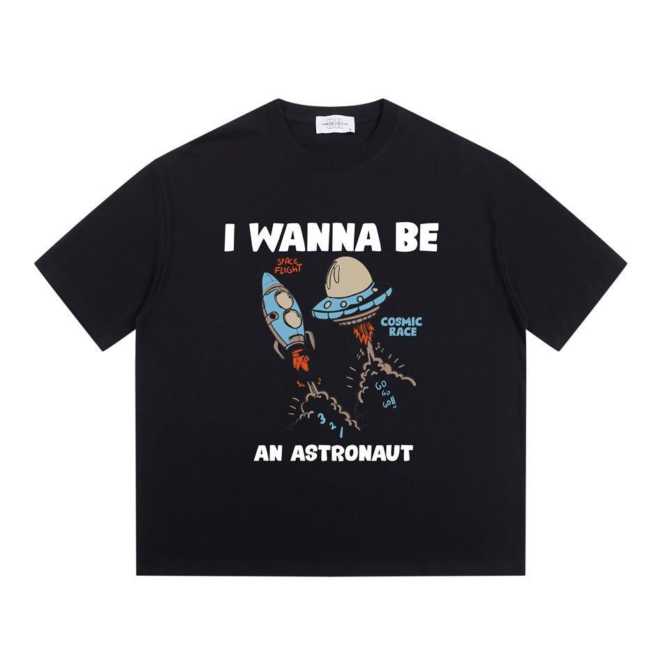 Black short-sleeve crew-neck T-shirt with cartoon rocket and UFO 'I WANNA BE AN ASTRONAUT' graphic, flat lay