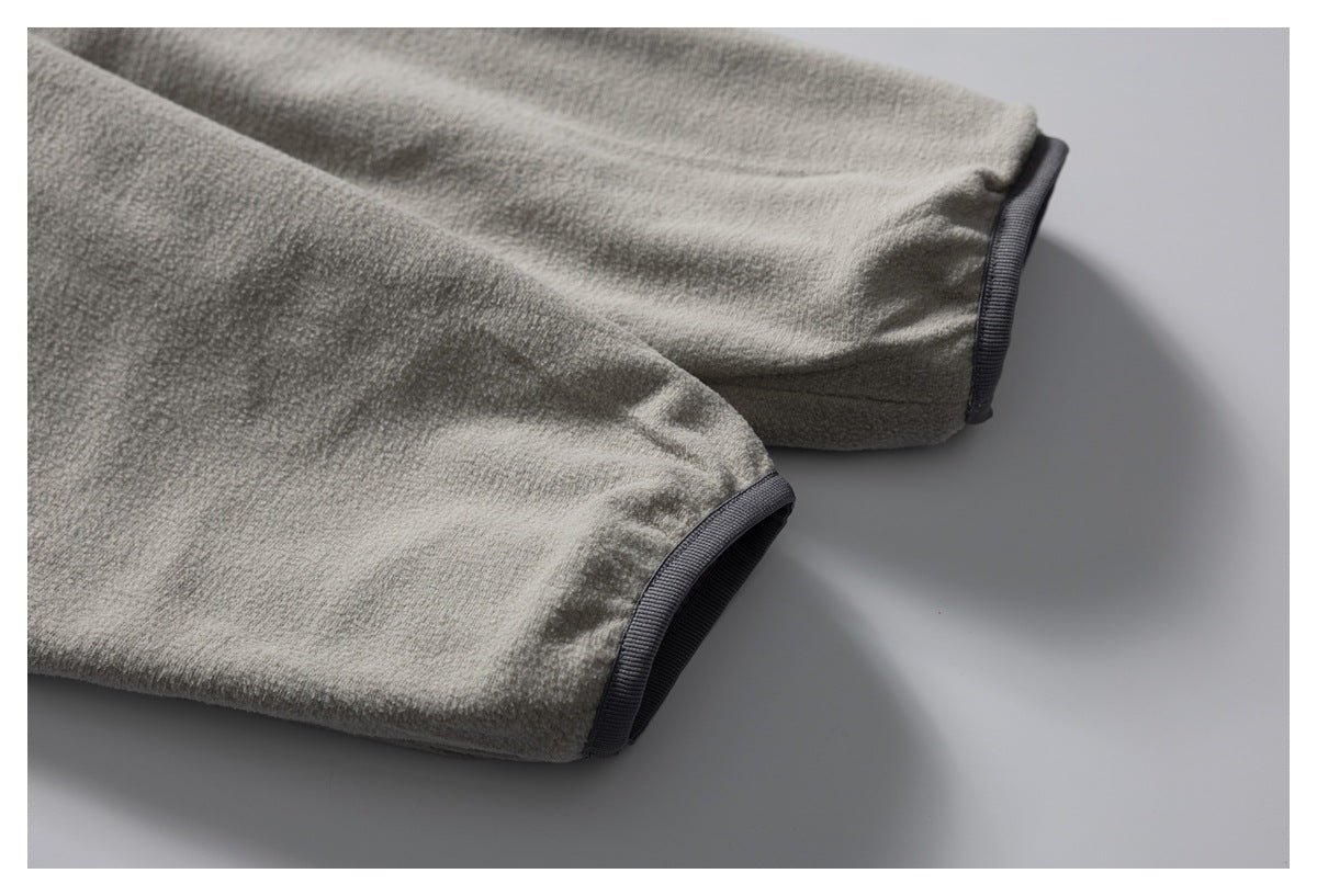 Close-up of two gray fleece jacket sleeves showing dark trim at the cuffs.