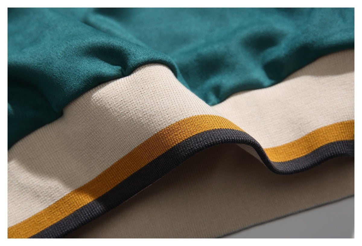 Close-up of a teal garment hem with a wide cream ribbed band and mustard and charcoal stripes.