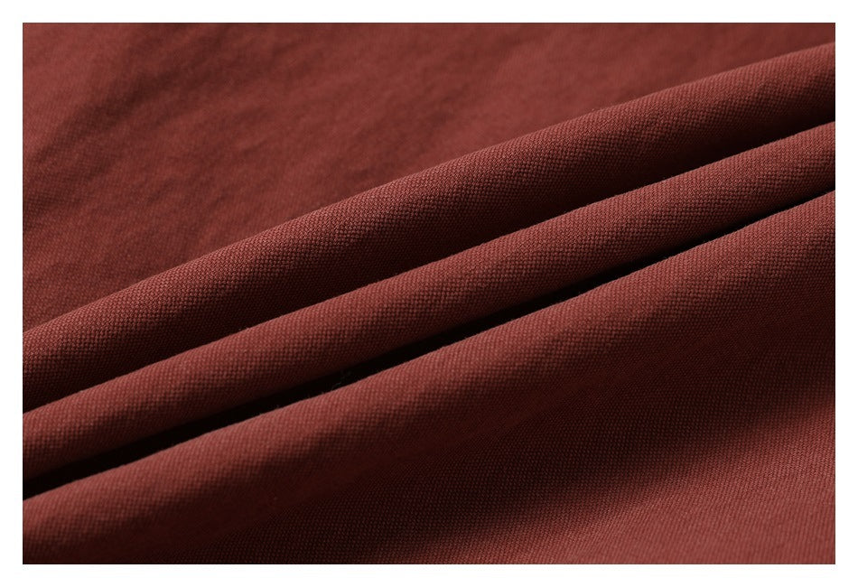 Macro view of rust-red garment fabric folded to show its fine textured surface.