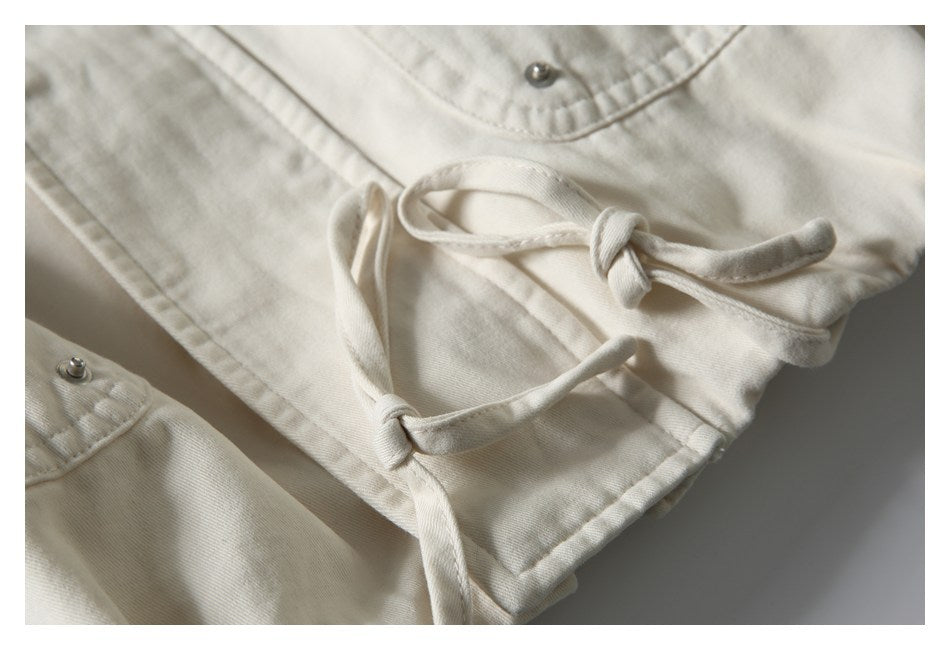 Close-up of cream drawstrings tied at the hem of a jacket.