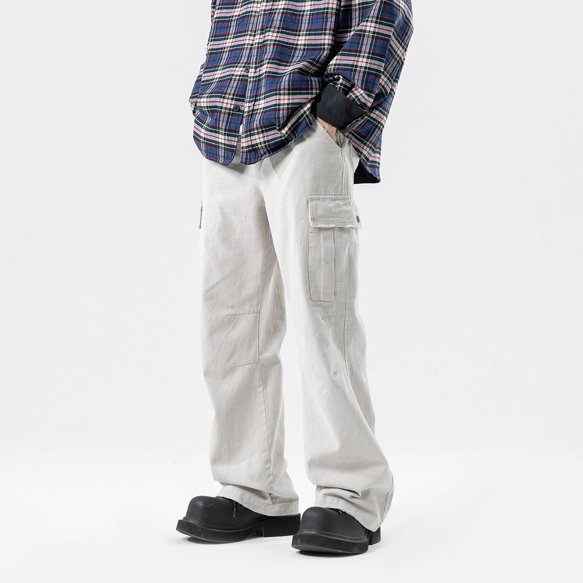 Front three-quarter view of a model wearing loose light gray cargo pants with a flap thigh pocket and black shoes.