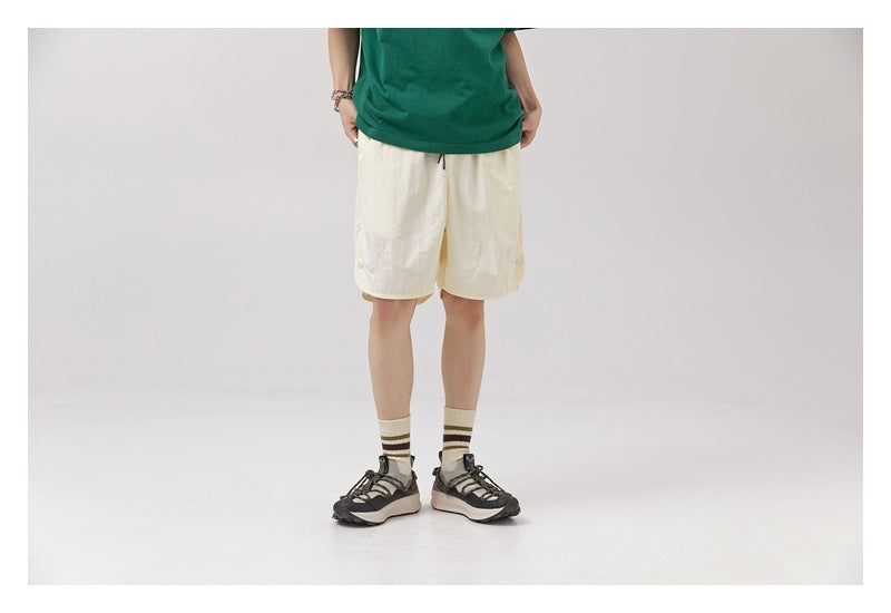 Front view of a model wearing off-white knee-length shorts with a drawstring waist.