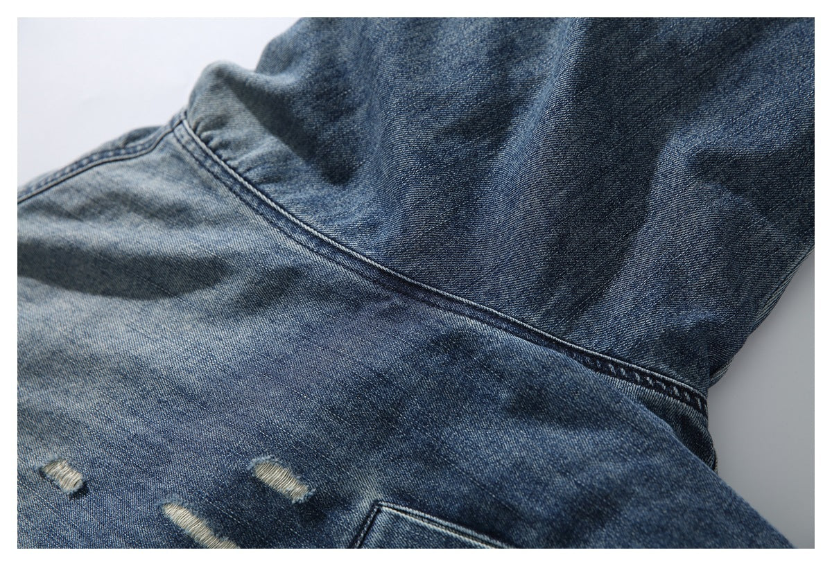 Close-up of a blue denim jacket back seam, distressed marks, and part of a pocket.