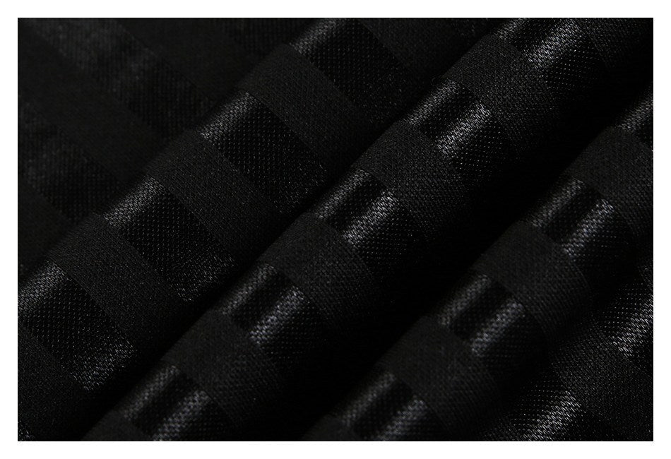 Close-up of black fabric with a raised, woven texture and diagonal folds.