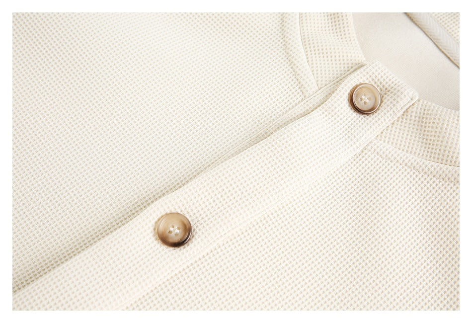 Close-up of the cream textured knit and its buttoned front placket.