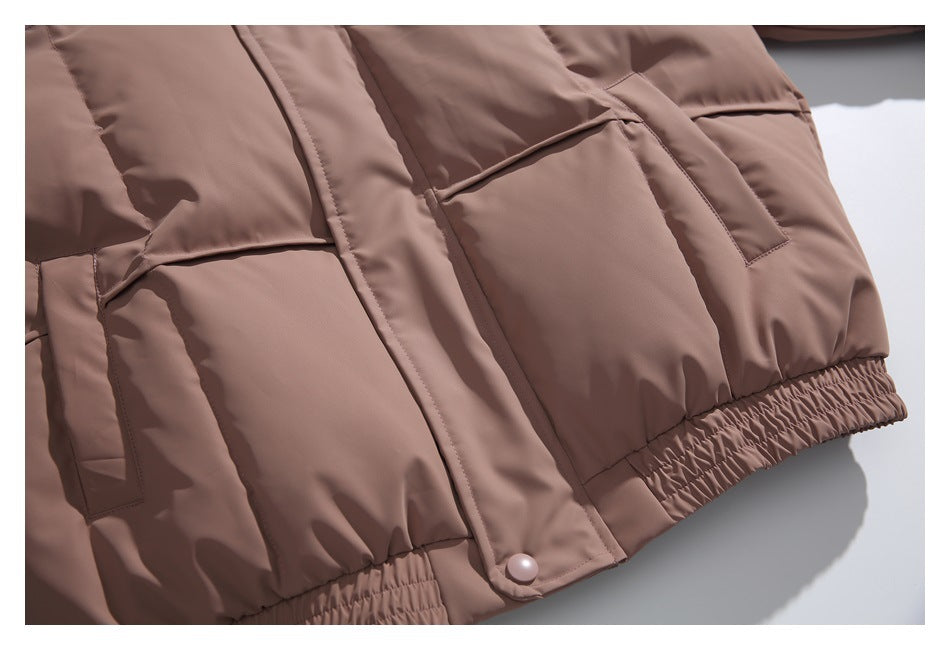 Lower front of a taupe-brown jacket with two flap pockets, a snap tab, and gathered elastic hem.