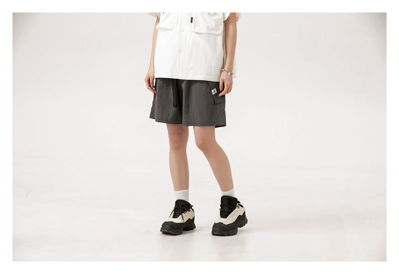 Cropped model wearing charcoal gray drawstring shorts with side pockets, shown from the front.