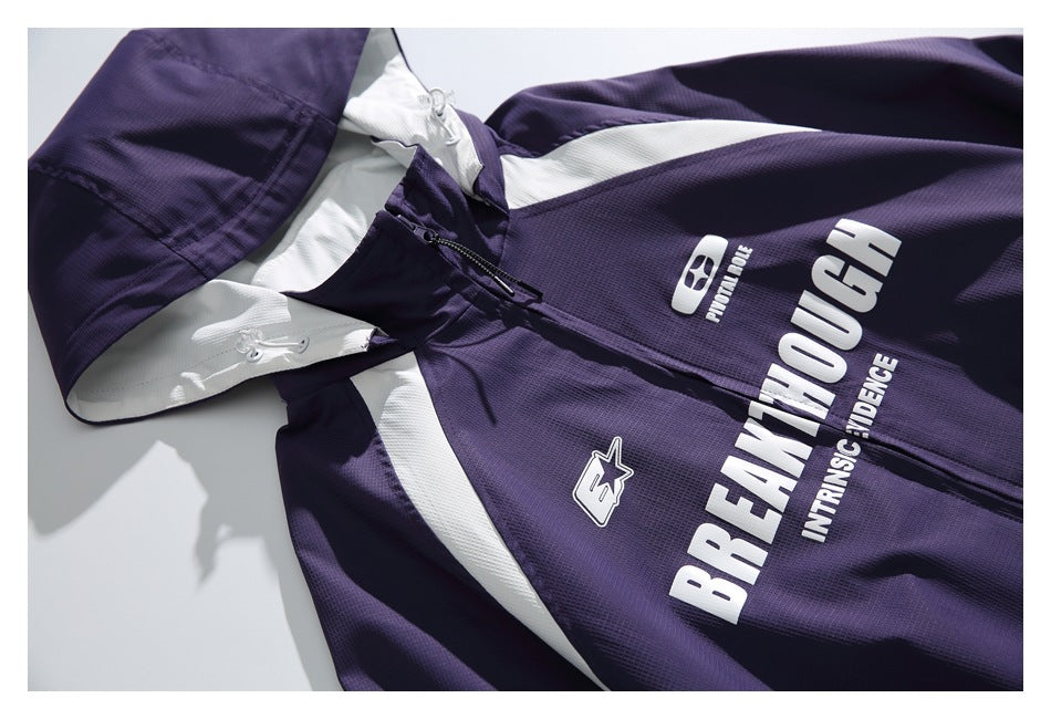 Angled close-up of a purple hooded zip jacket with white panels and large white lettering on the front.