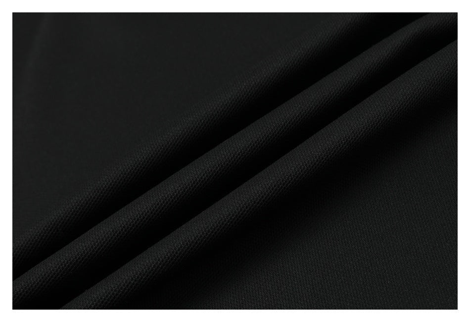 Close-up of black fabric with a subtle textured weave arranged in diagonal folds.