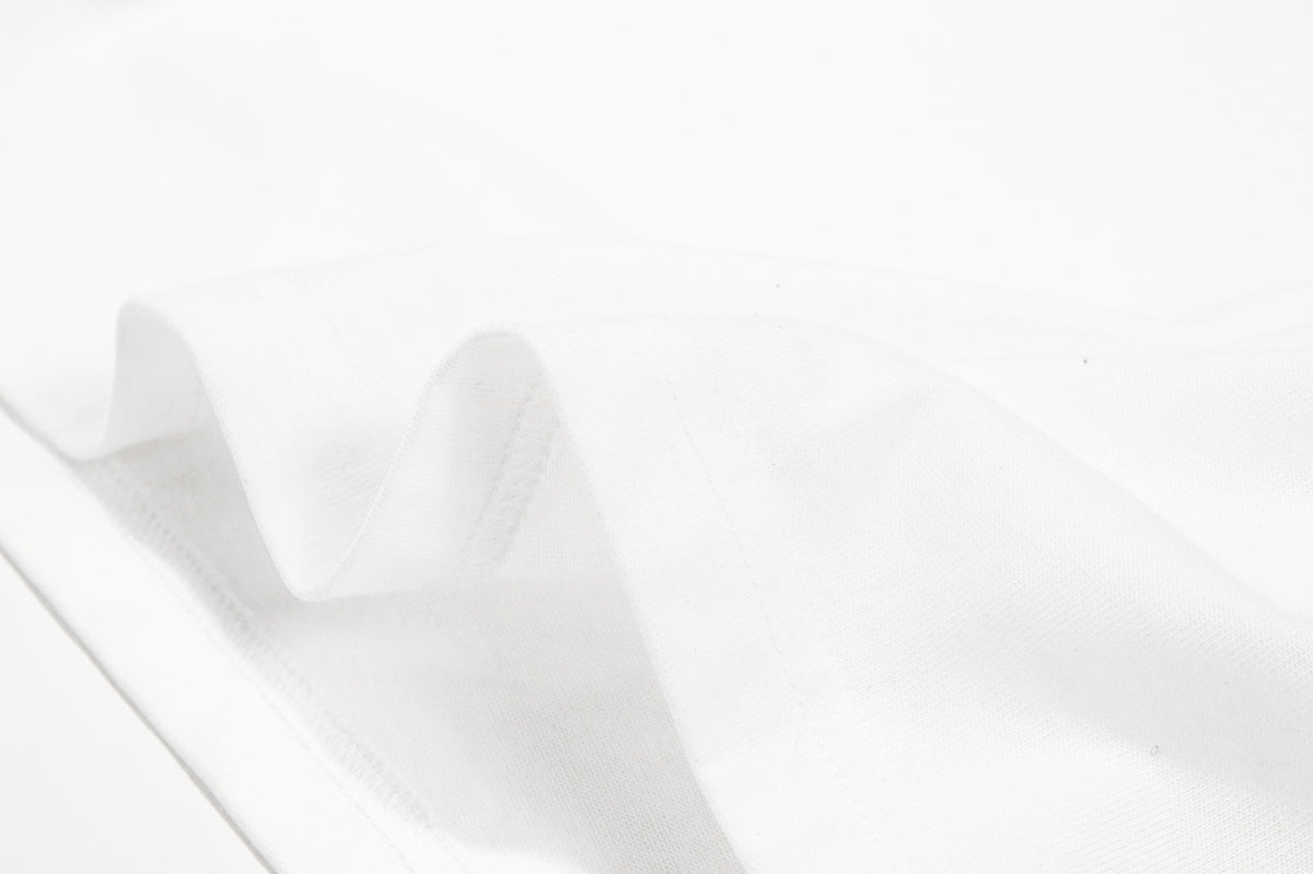 Close-up of white fabric folded into soft waves, with a stitched edge visible along one side.