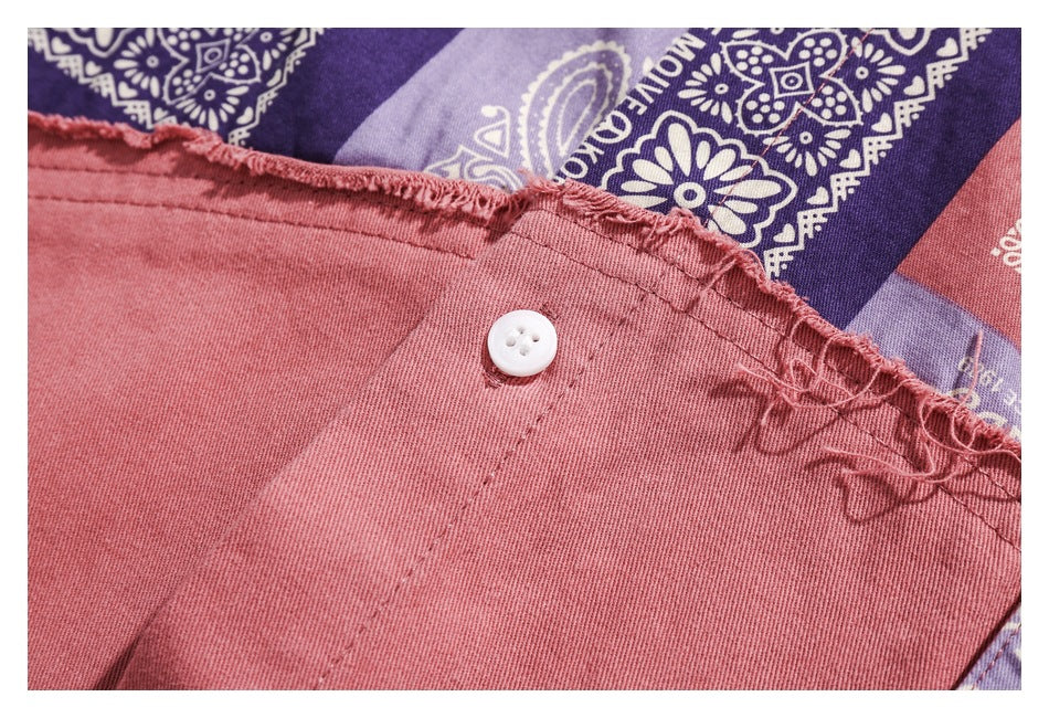 Close-up of a white button and frayed edge beside the shirt's purple and pink bandana-print panel.