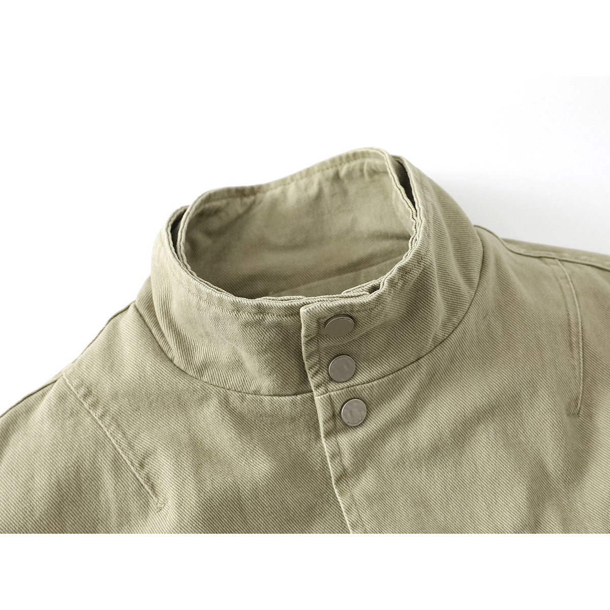 Close-up of a khaki jacket's tall stand collar with three metal snaps and stitched shoulder seams.