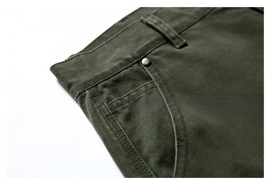 Close-up of olive green trouser pocket stitching, a metal rivet, and a belt loop.