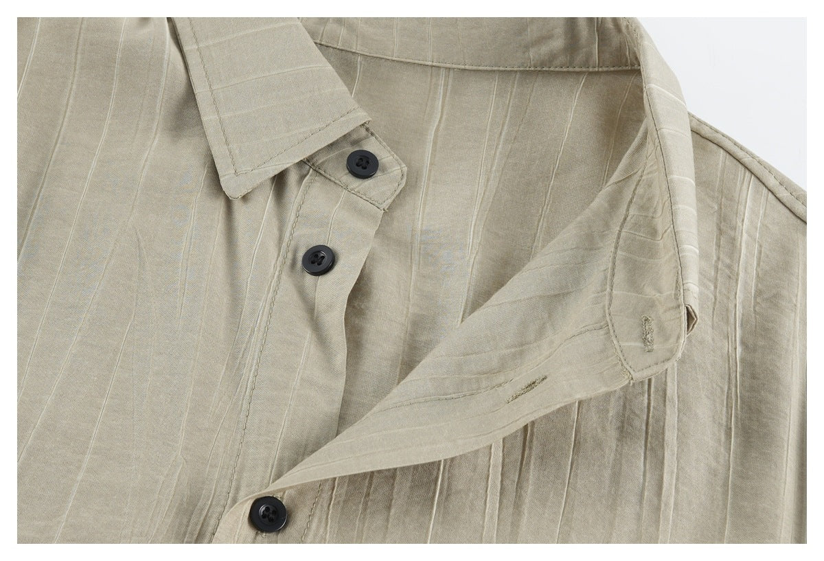 Close-up of a beige vertically textured button-up shirt showing its placket, dark buttons and collar edge.