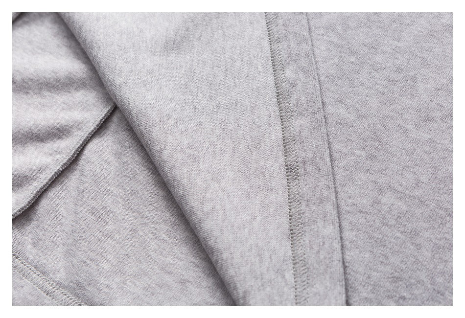 Close-up of heather-gray garment fabric with an overlocked seam and folded fabric edge.