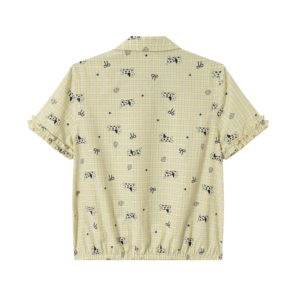 Back view of pale yellow plaid short-sleeve shirt with navy dog and bow print, ruffled sleeve cuffs and elasticated hem