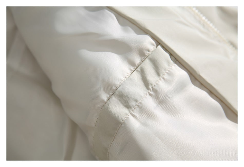 Close-up of a stitched seam and gathered fabric on the ivory jacket.