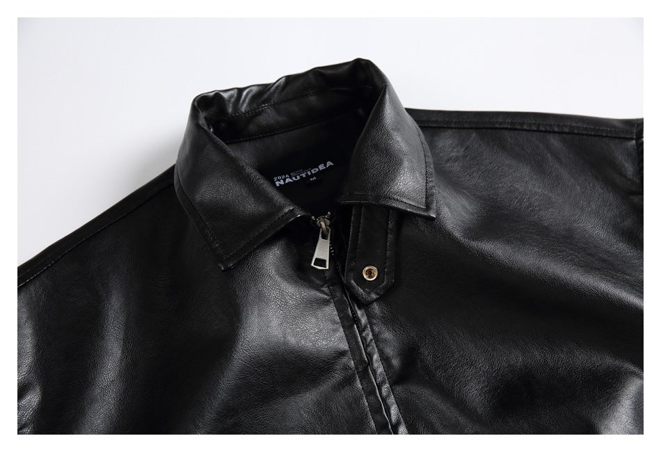 Close-up of a black jacket’s pointed collar, front zipper, and snap-tab detail.