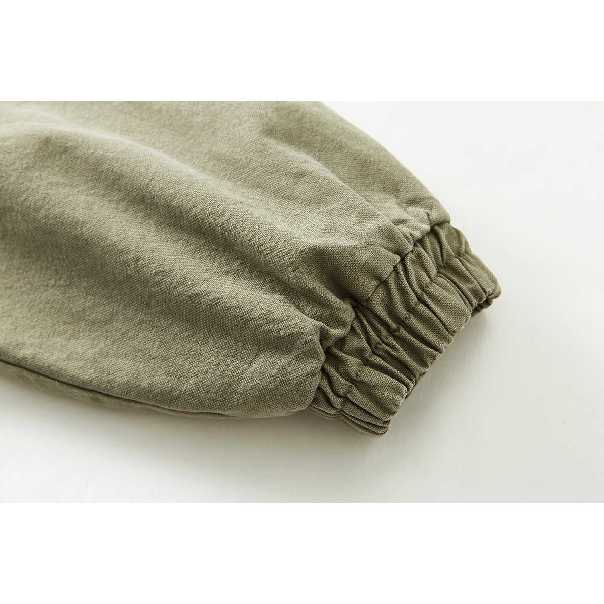 Close-up of an olive-khaki jacket sleeve with a gathered elastic cuff.