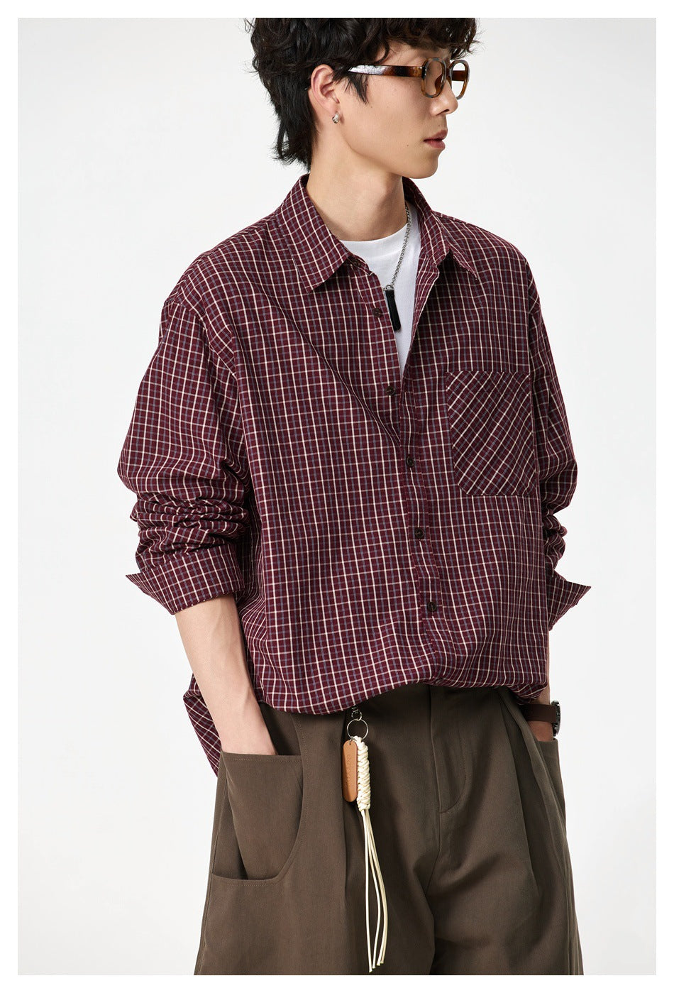 Model wearing the dark red check shirt open over a white tee, close-up of the pocket and rolled sleeves