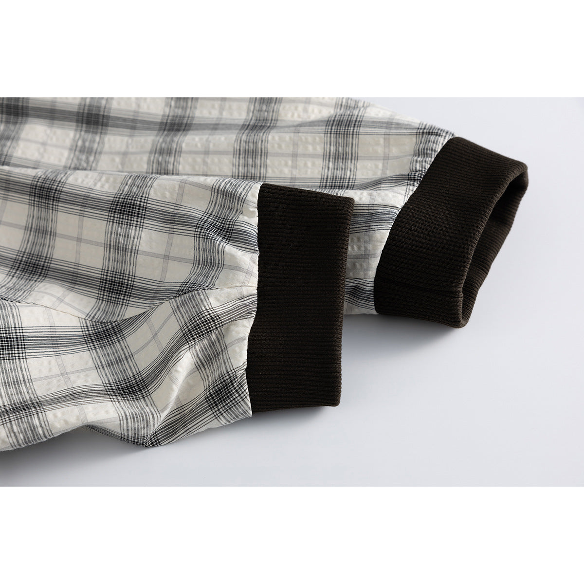Close-up of the plaid jacket sleeve ending in a wide dark brown ribbed cuff.