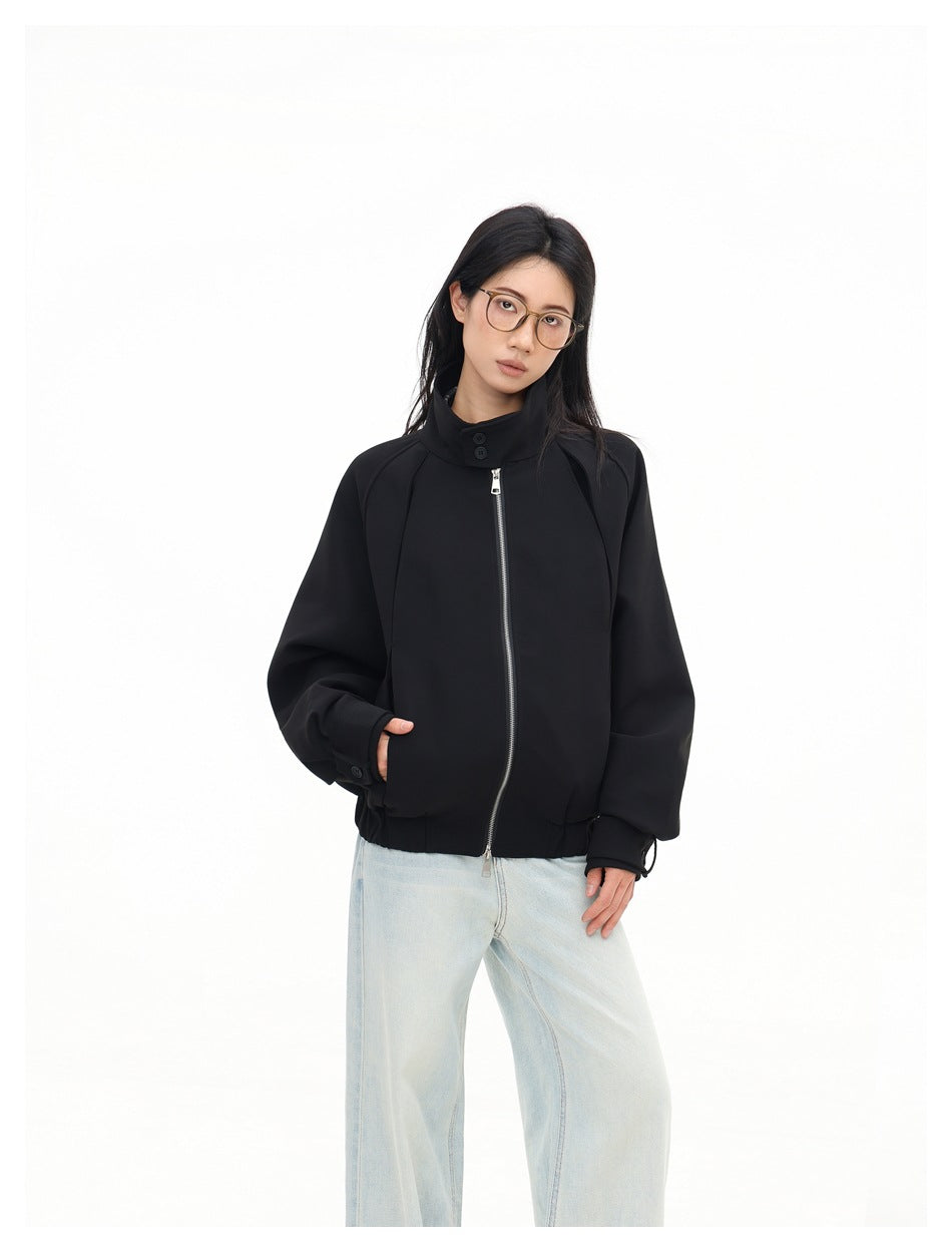 Closer view of a model wearing a black zip-front jacket with a high button collar and oversized sleeves.