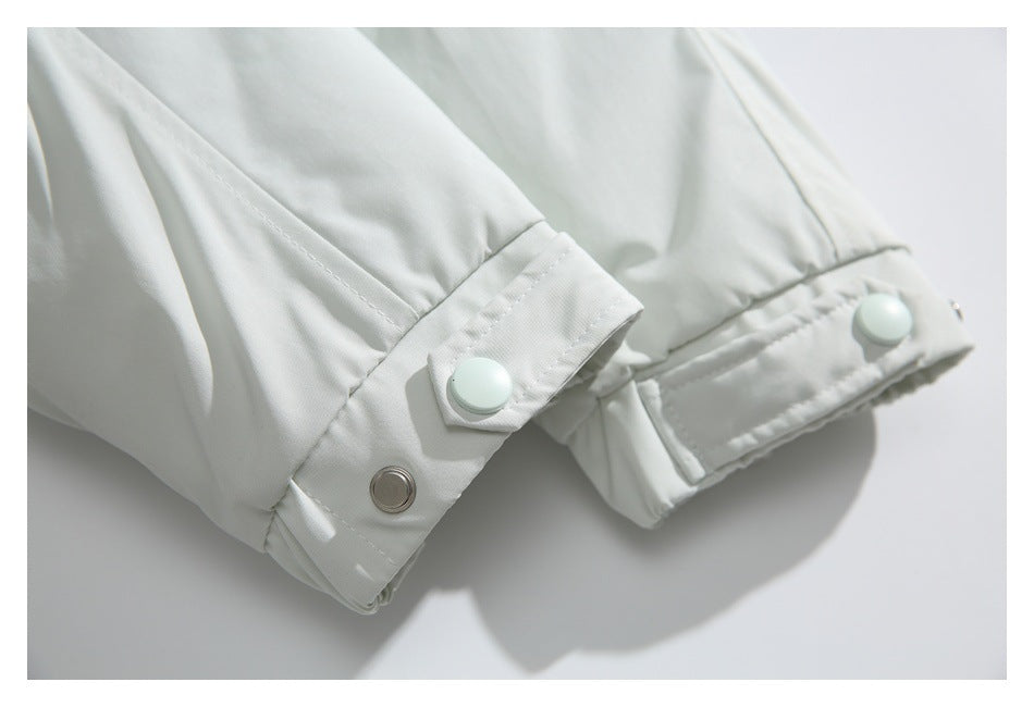 Close-up of a white jacket sleeve cuff with snap fasteners.