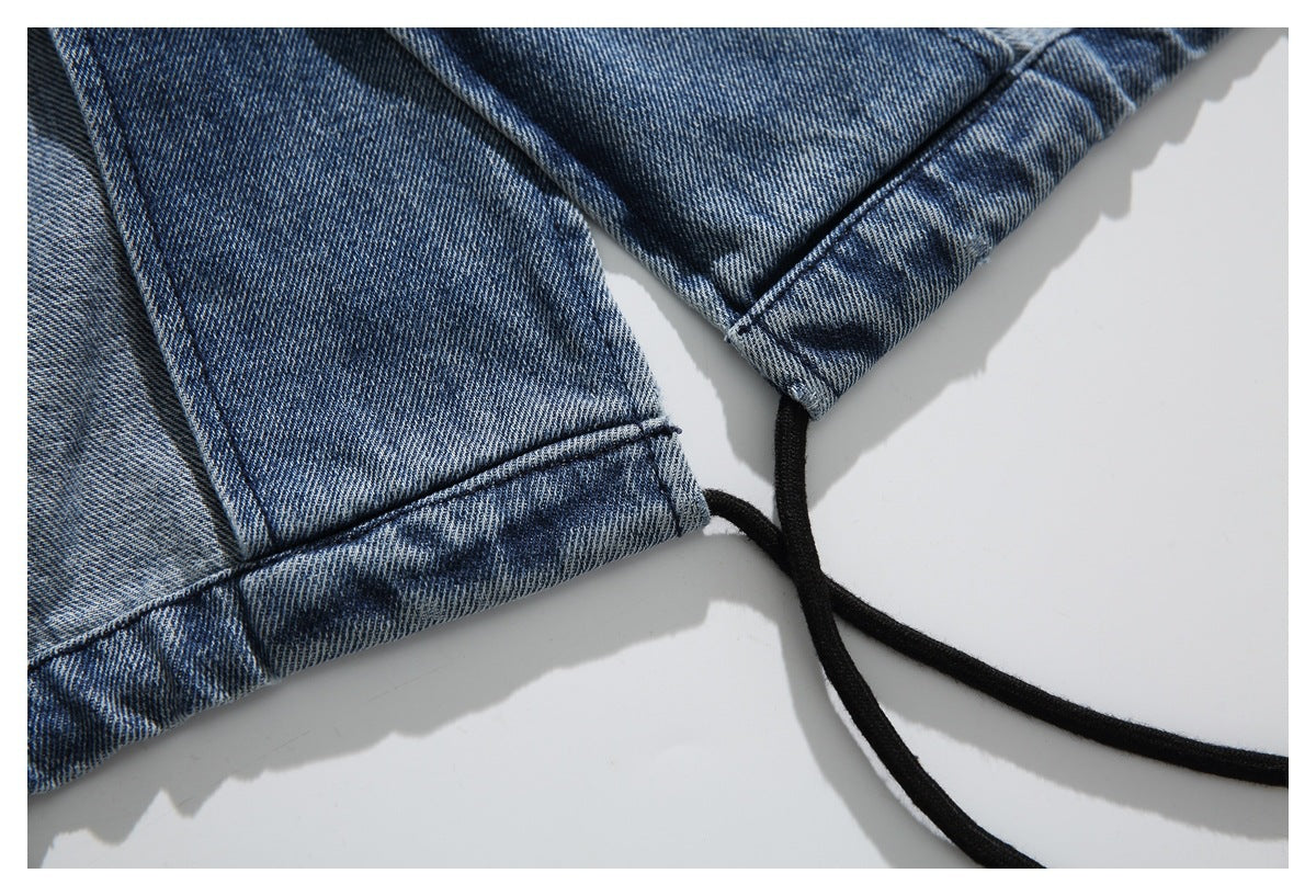 Close-up of blue denim stitching and hem beside a black drawcord.